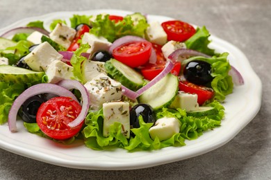 Photo of Delicious salad with feta cheese on gray textured table, closeup