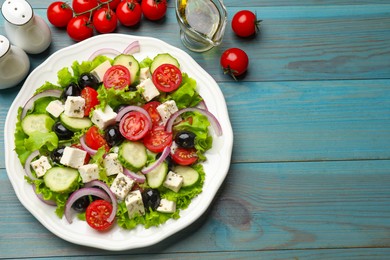 Photo of Delicious salad with feta cheese and ingredients on light blue wooden table, flat lay. Space for text