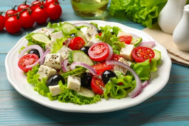 Photo of Delicious salad with feta cheese and ingredients on light blue wooden table, closeup