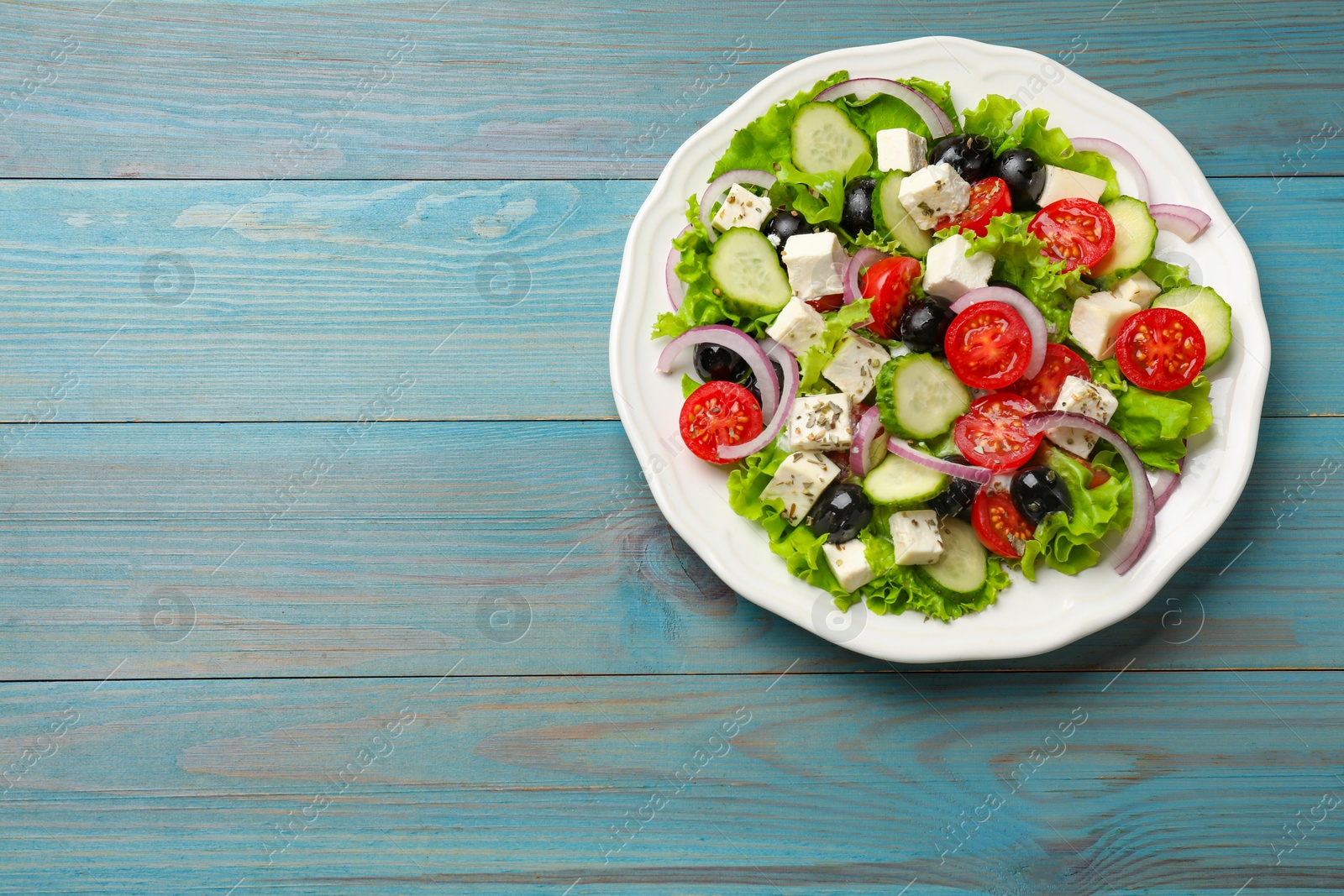 Photo of Delicious salad with feta cheese on light blue wooden table, top view. Space for text