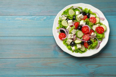 Photo of Delicious salad with feta cheese on light blue wooden table, top view. Space for text