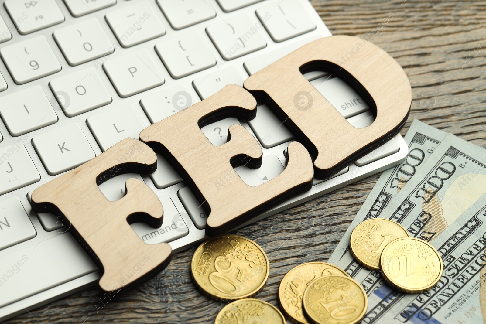 Photo of Word Fed (Federal Reserve System) made with letters, keyboard, dollar banknotes and coins on wooden table, closeup