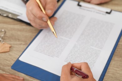 Real estate agent working with client at wooden table, closeup