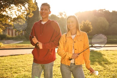 Photo of Young man and woman with badminton rackets and shuttlecock in park on sunny day