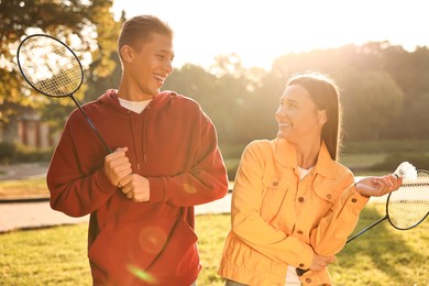 Photo of Young man and woman with badminton rackets and shuttlecock in park on sunny day