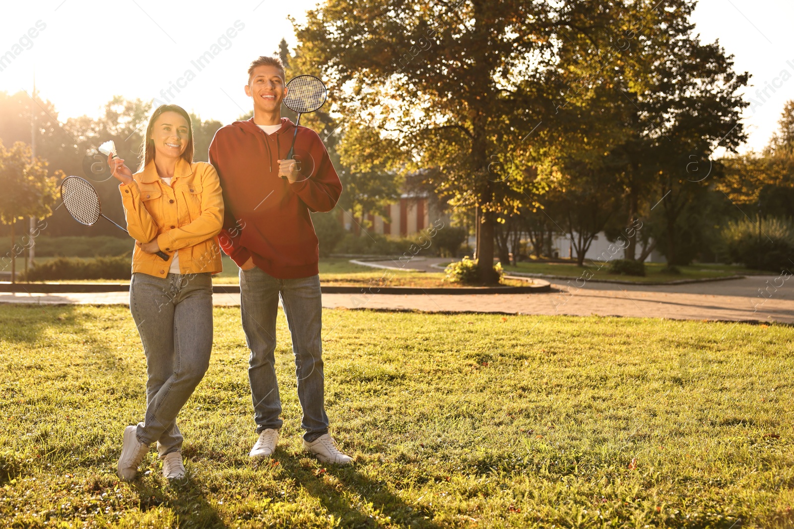 Photo of Young man and woman with badminton rackets and shuttlecock in park on sunny day