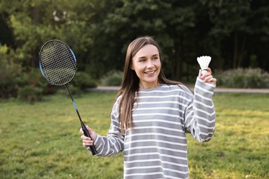 Photo of Happy young woman with badminton racket and shuttlecock in park