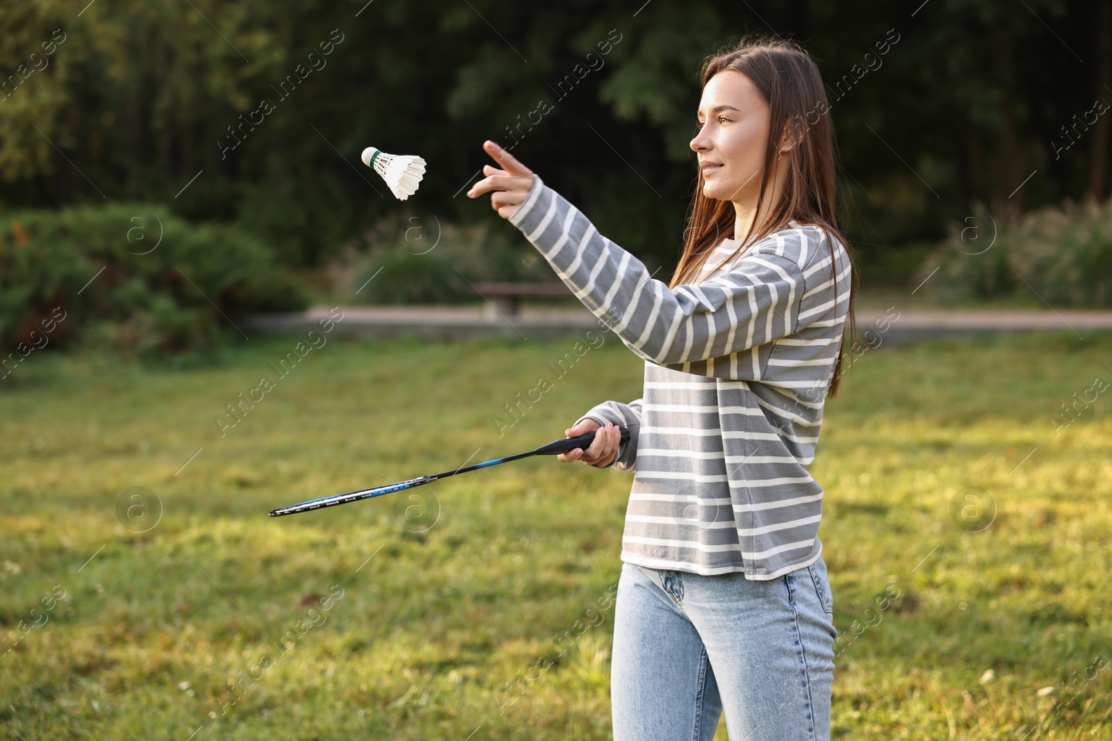 Photo of Young woman playing badminton racket in park