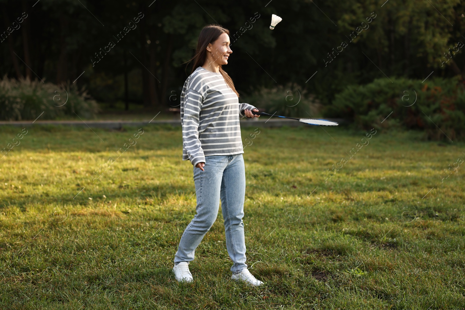 Photo of Young woman playing badminton racket in park