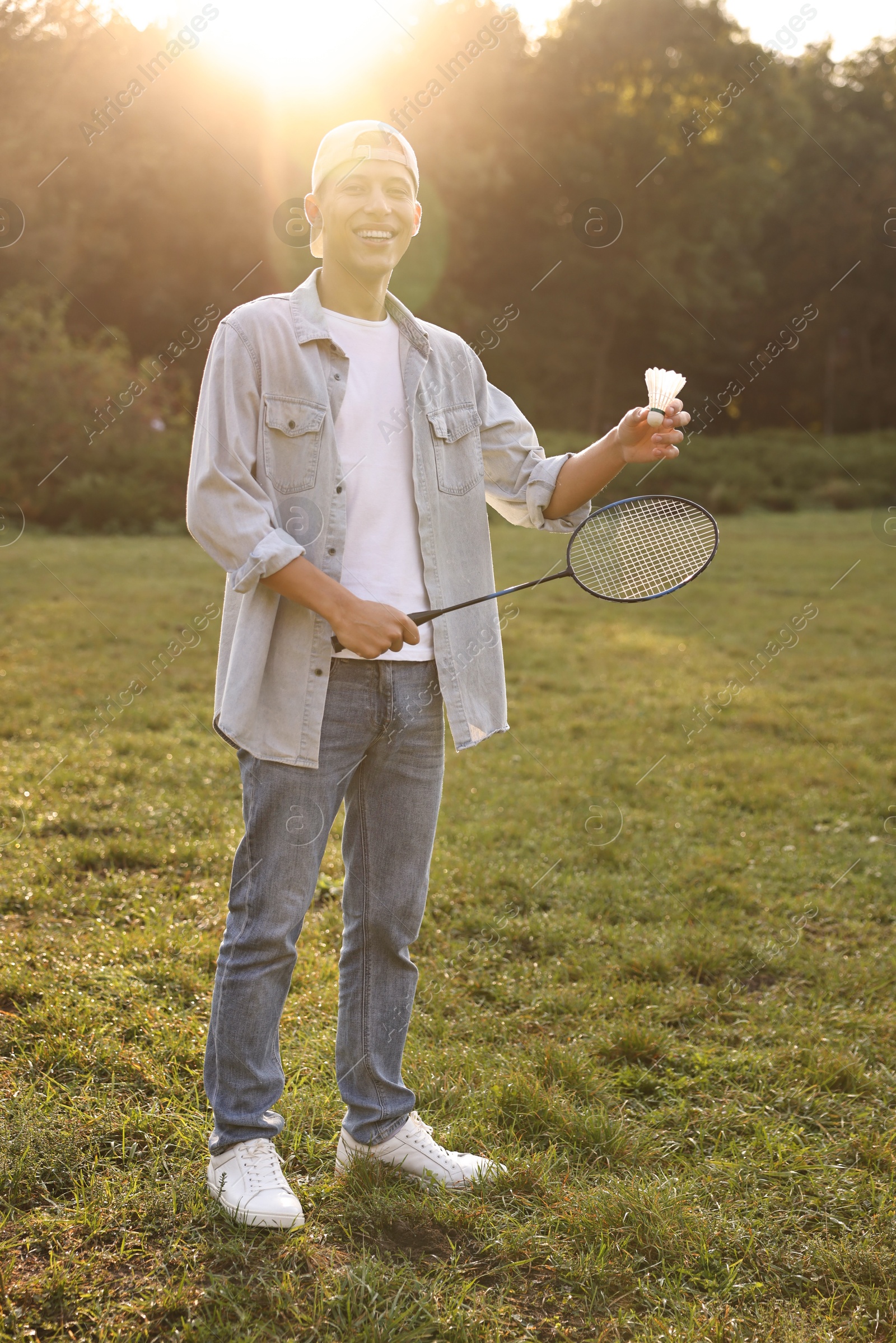 Photo of Happy young man with badminton racket and shuttlecock in park on sunny day