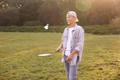 Young man playing badminton racket in park on sunny day