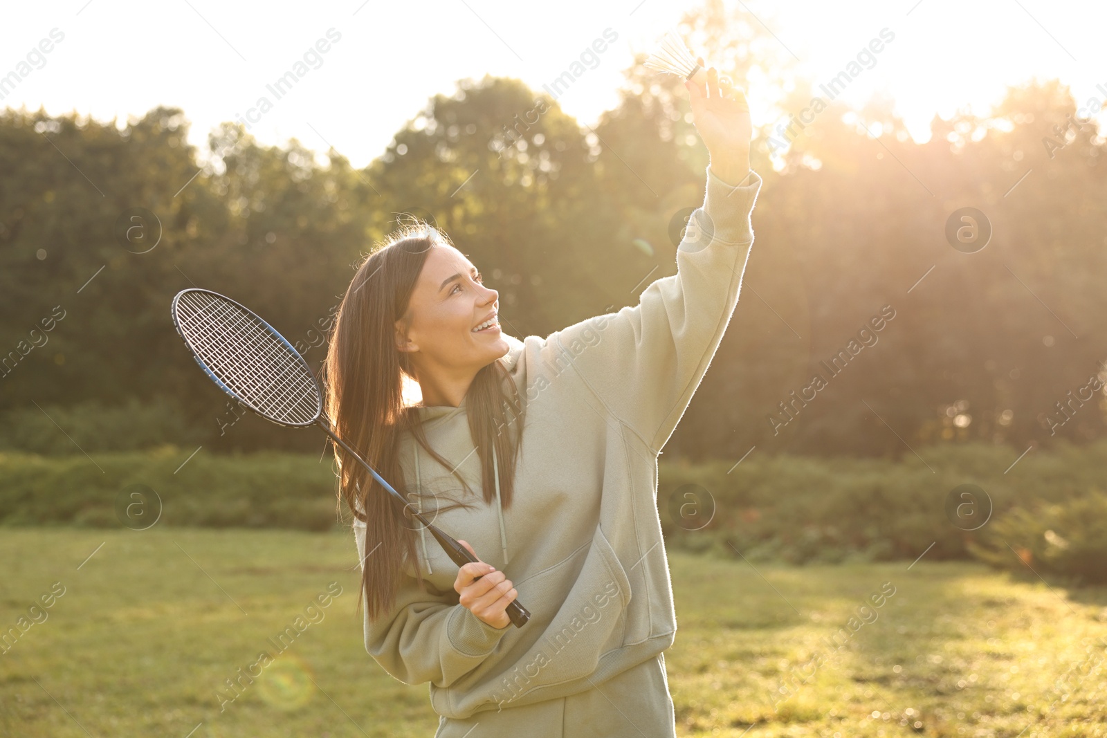 Photo of Happy young woman playing badminton racket in park on sunny day