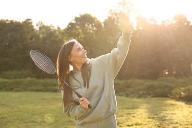 Photo of Happy young woman playing badminton racket in park on sunny day