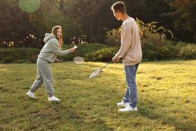 Photo of Young woman and man playing badminton in park on sunny day, selective focus