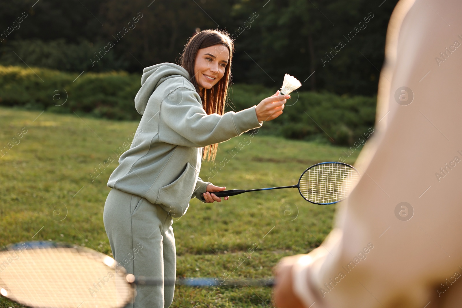 Photo of Young woman and man playing badminton in park, selective focus