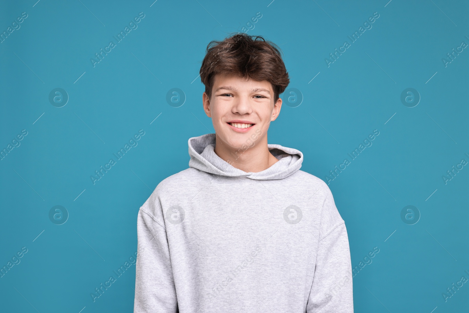 Photo of Portrait of happy teenage boy on light blue background