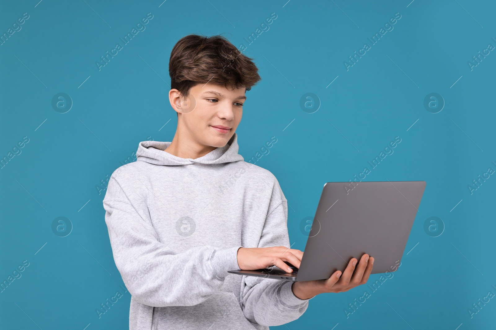 Photo of Teenage boy with laptop on light blue background