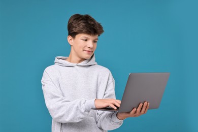 Photo of Teenage boy with laptop on light blue background