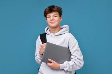 Photo of Teenage boy with laptop and backpack on light blue background