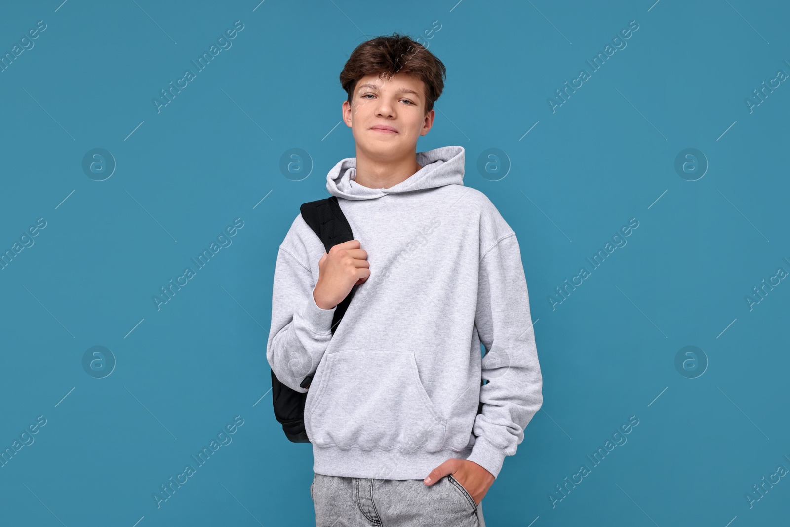 Photo of Teenage boy with backpack on light blue background