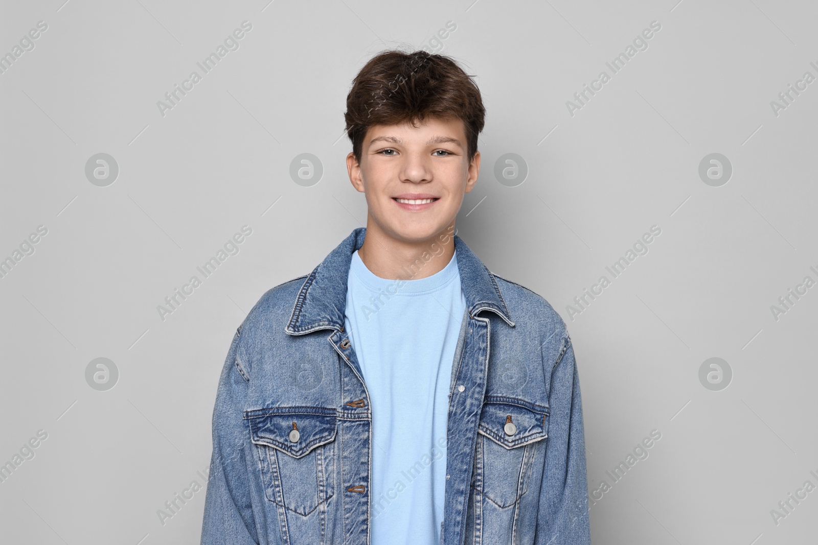 Photo of Portrait of happy teenage boy on light grey background