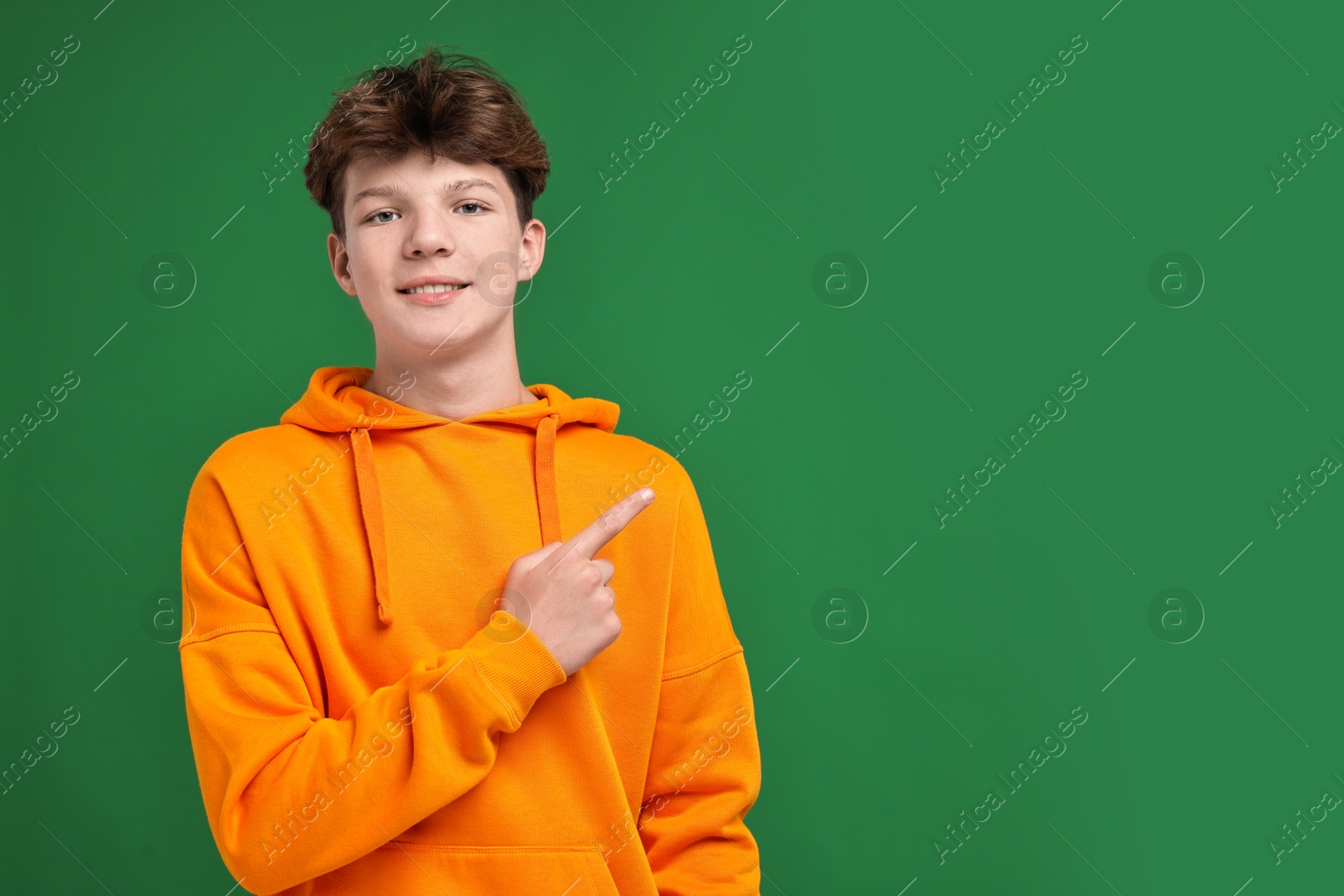 Photo of Portrait of happy teenage boy on green background, space for text