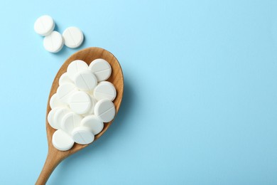 Photo of Antibiotic pills and spoon on light blue background, flat lay. Space for text