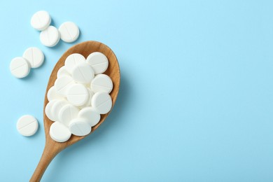 Photo of Antibiotic pills and spoon on light blue background, flat lay. Space for text