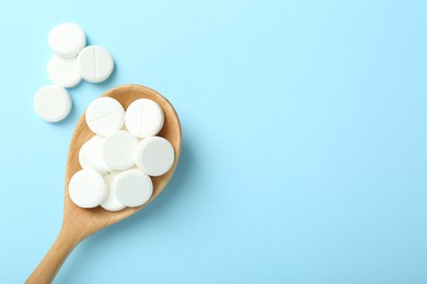 Photo of Antibiotic pills and spoon on light blue background, flat lay. Space for text