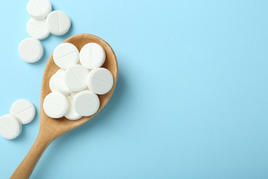 Photo of Antibiotic pills and spoon on light blue background, flat lay. Space for text