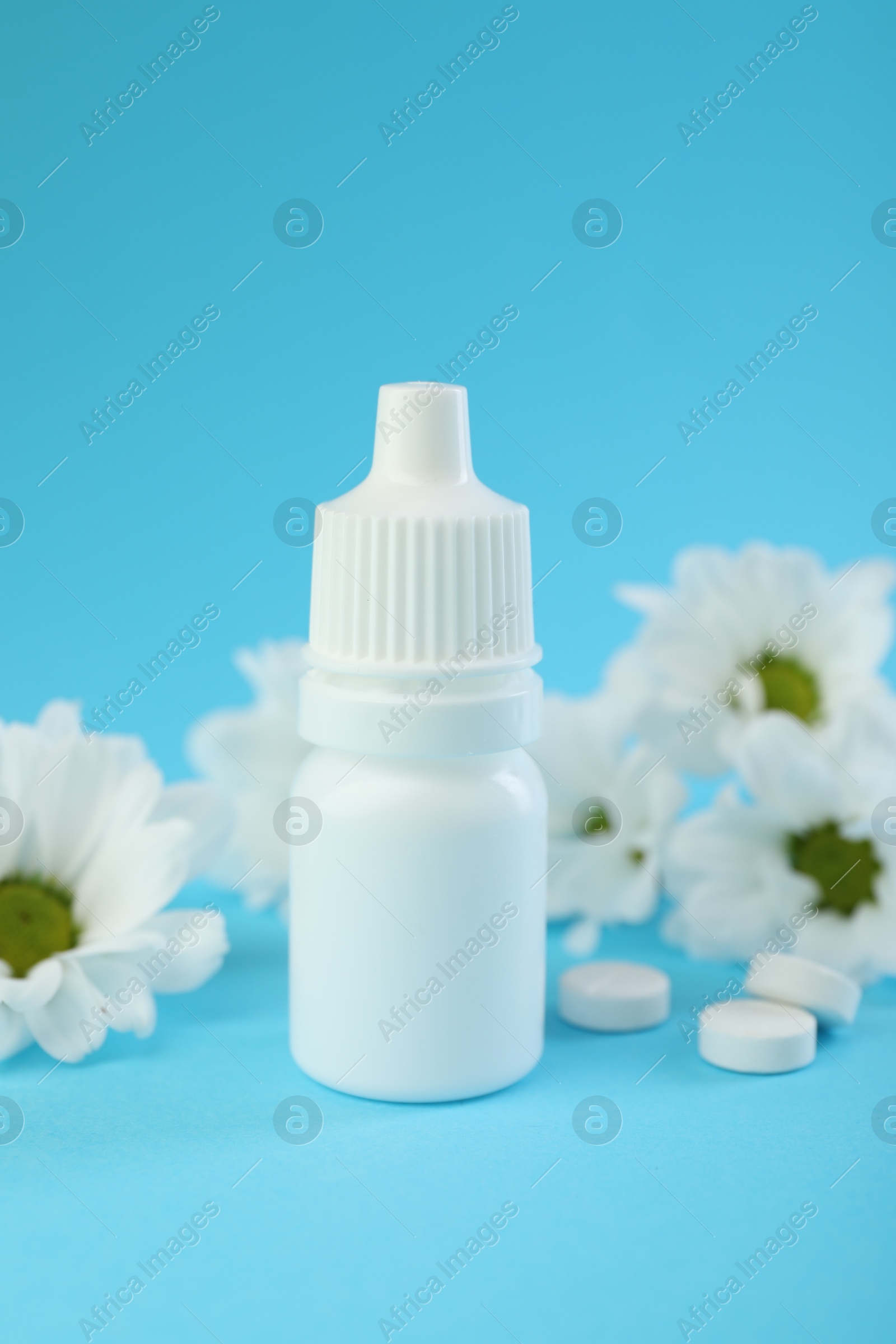 Photo of Allergy treatment. Nasal drops, pills and flowers on light blue background, closeup