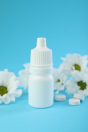 Photo of Allergy treatment. Nasal drops, pills and flowers on light blue background, closeup