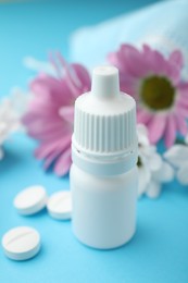 Photo of Allergy treatment. Nasal drops, pills and flowers on light blue background, closeup