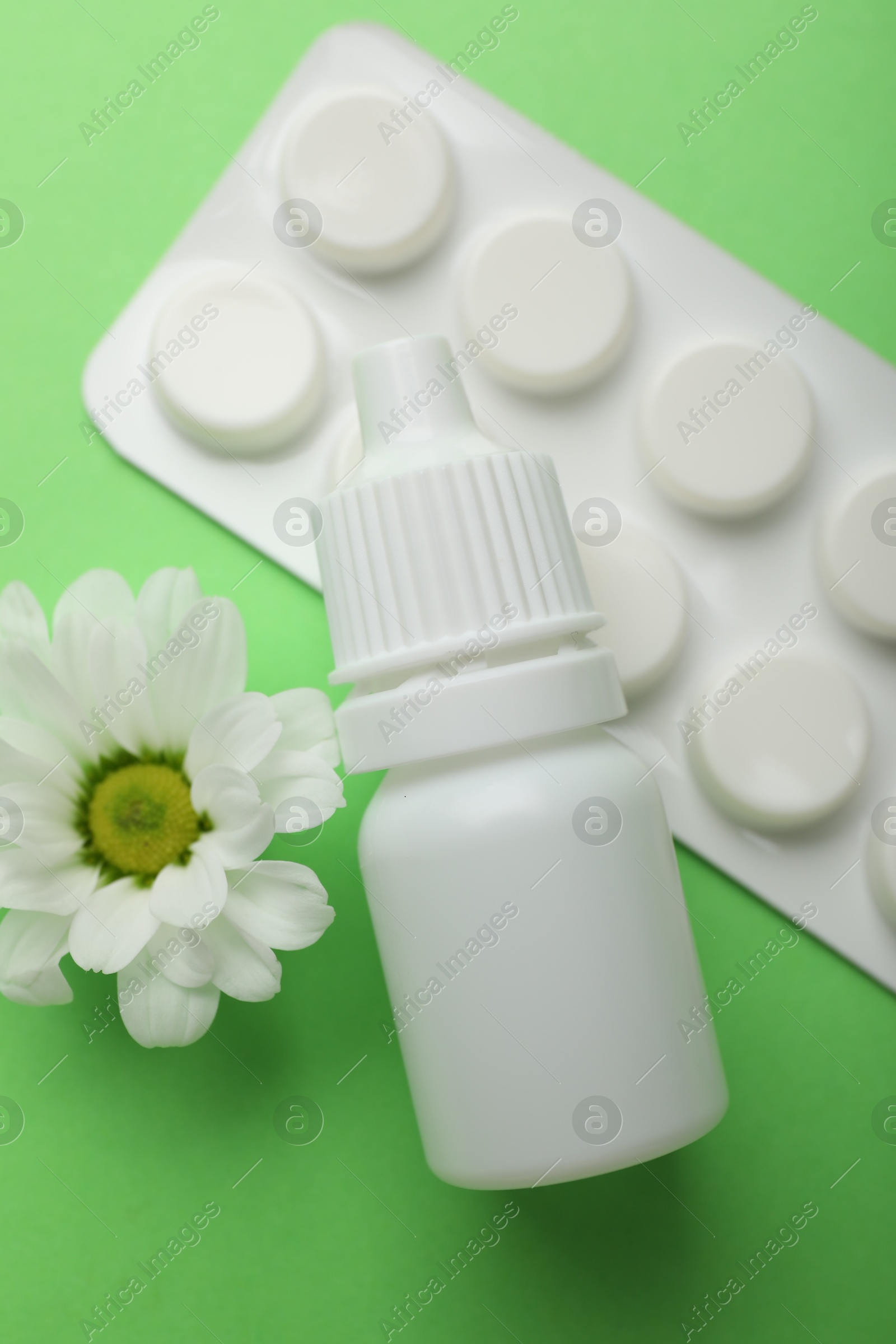 Photo of Allergy treatment. Nasal drops, pills and flower on green background, flat lay