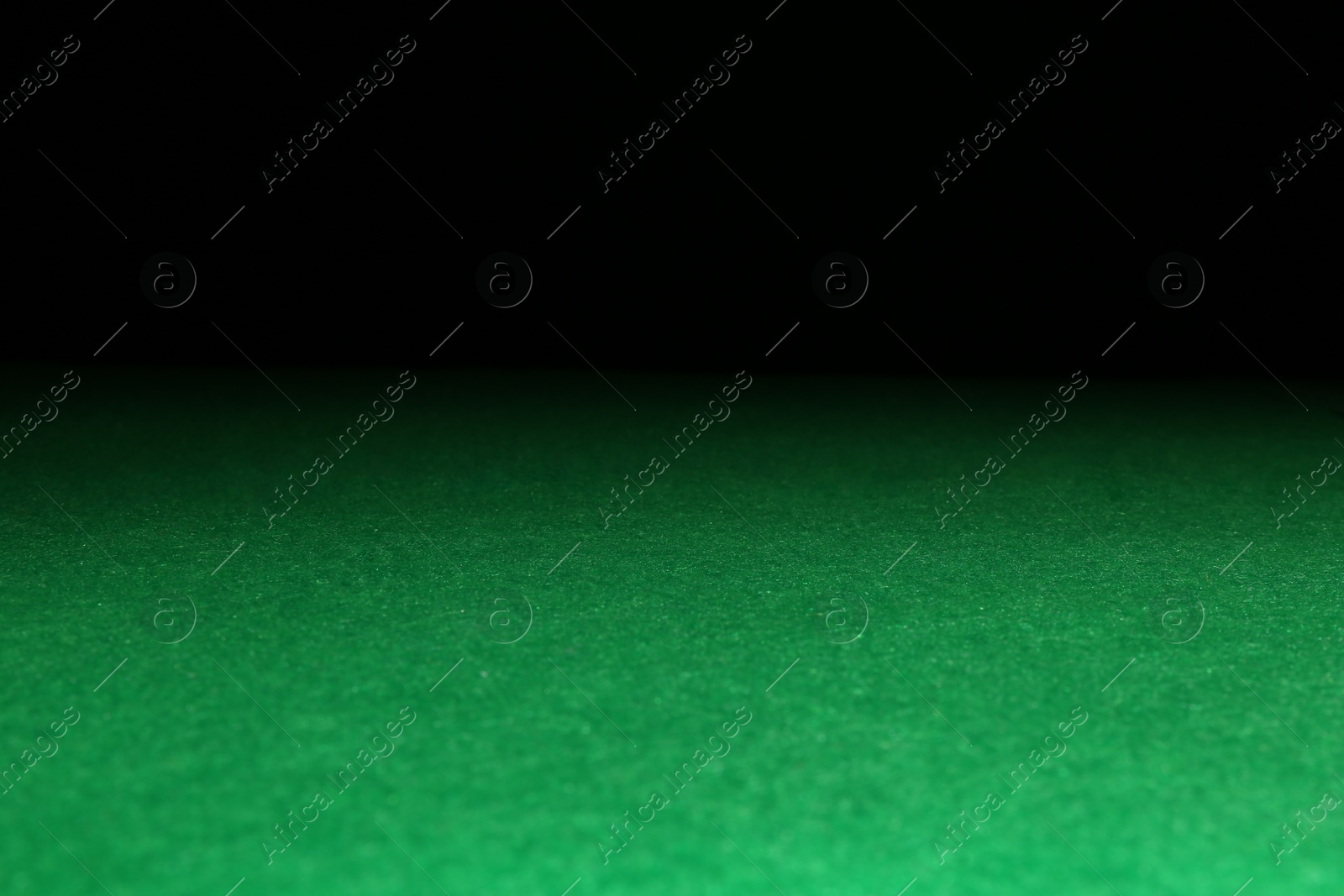 Photo of Green poker table against black background, closeup