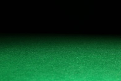 Photo of Green poker table against black background, closeup