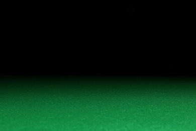 Photo of Green poker table against black background, closeup