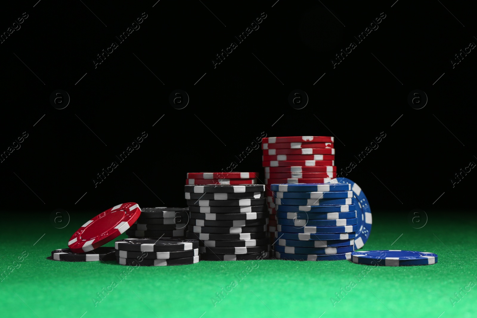 Photo of Poker chips on green table against dark background