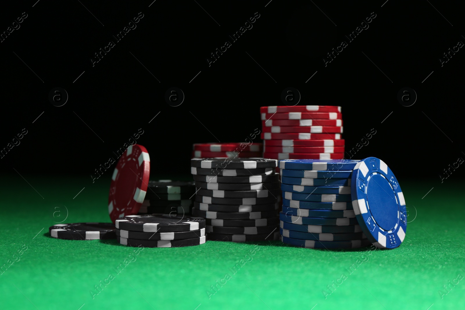 Photo of Poker chips on green table against dark background