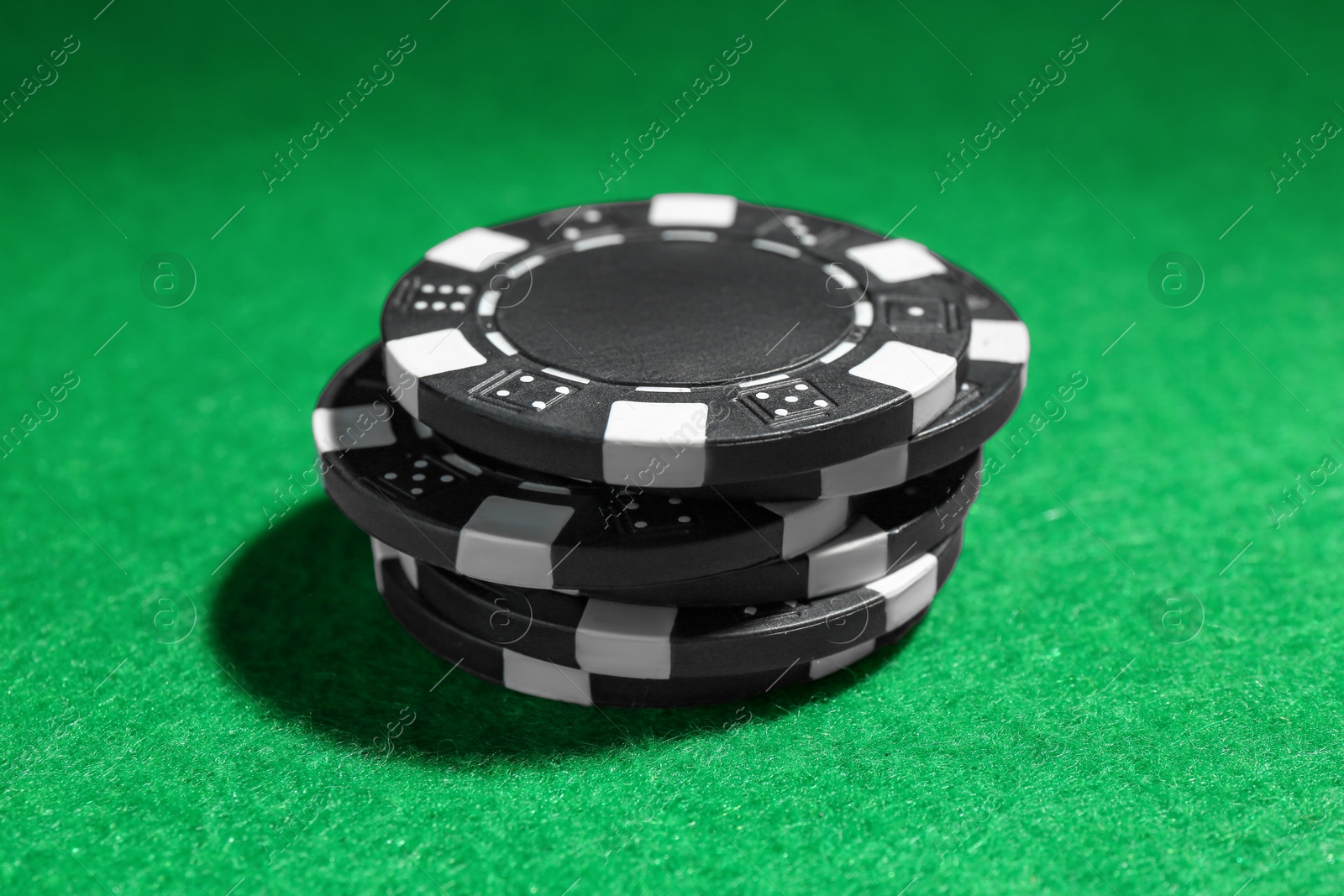 Photo of Stack of poker chips on green table, closeup