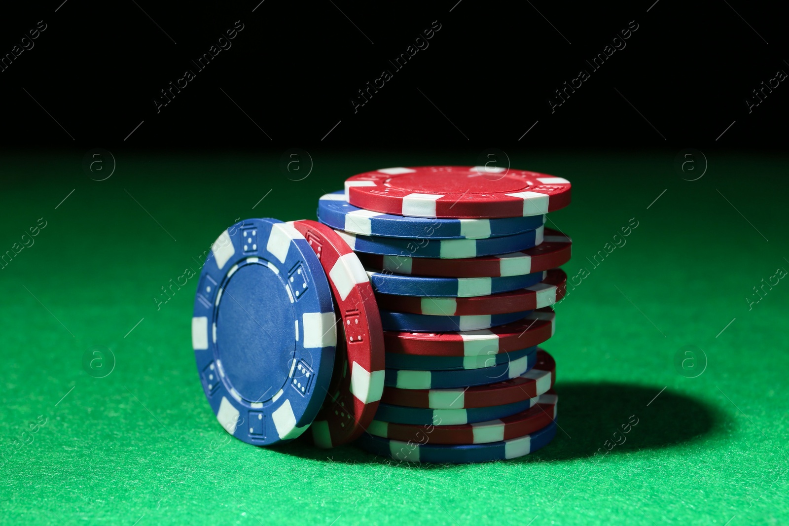 Photo of Poker chips on green table against dark background, closeup