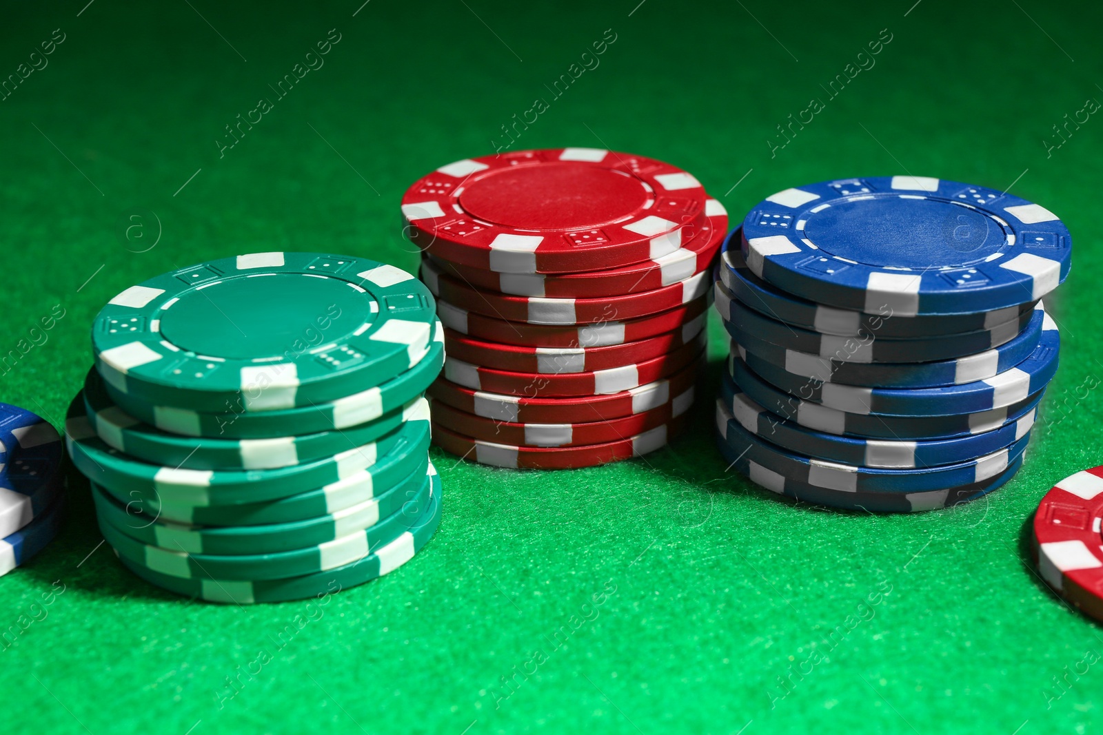 Photo of Stacks of poker chips on green table, closeup