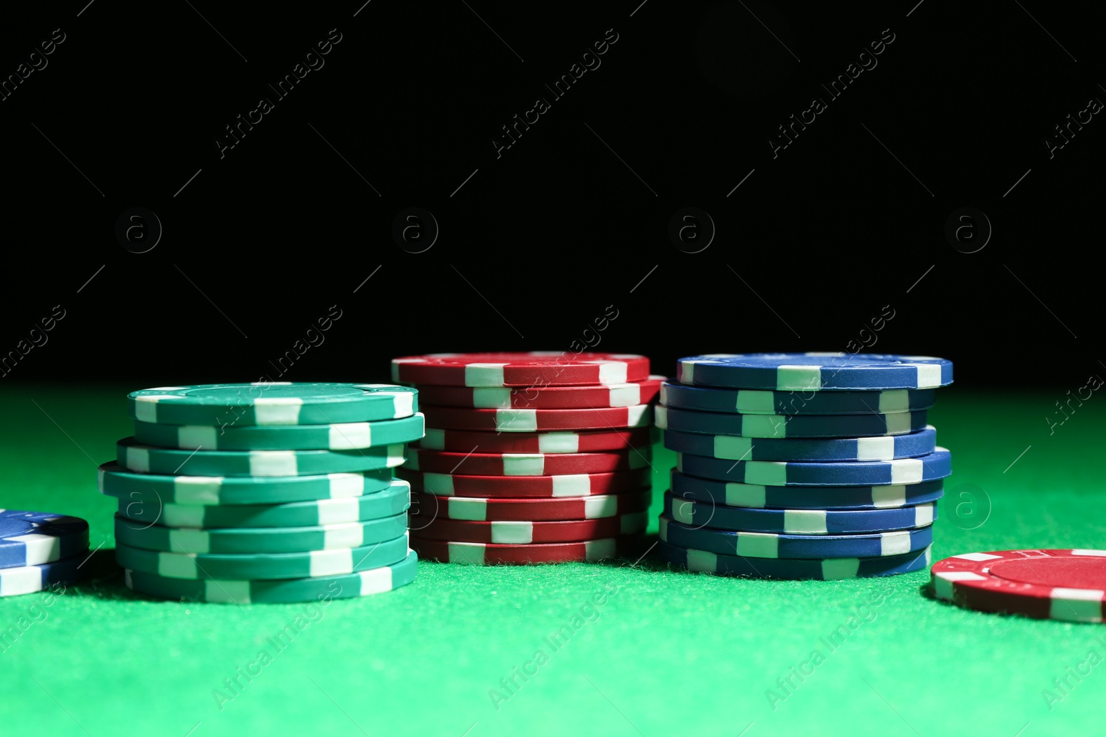 Photo of Poker chips on green table against dark background, closeup