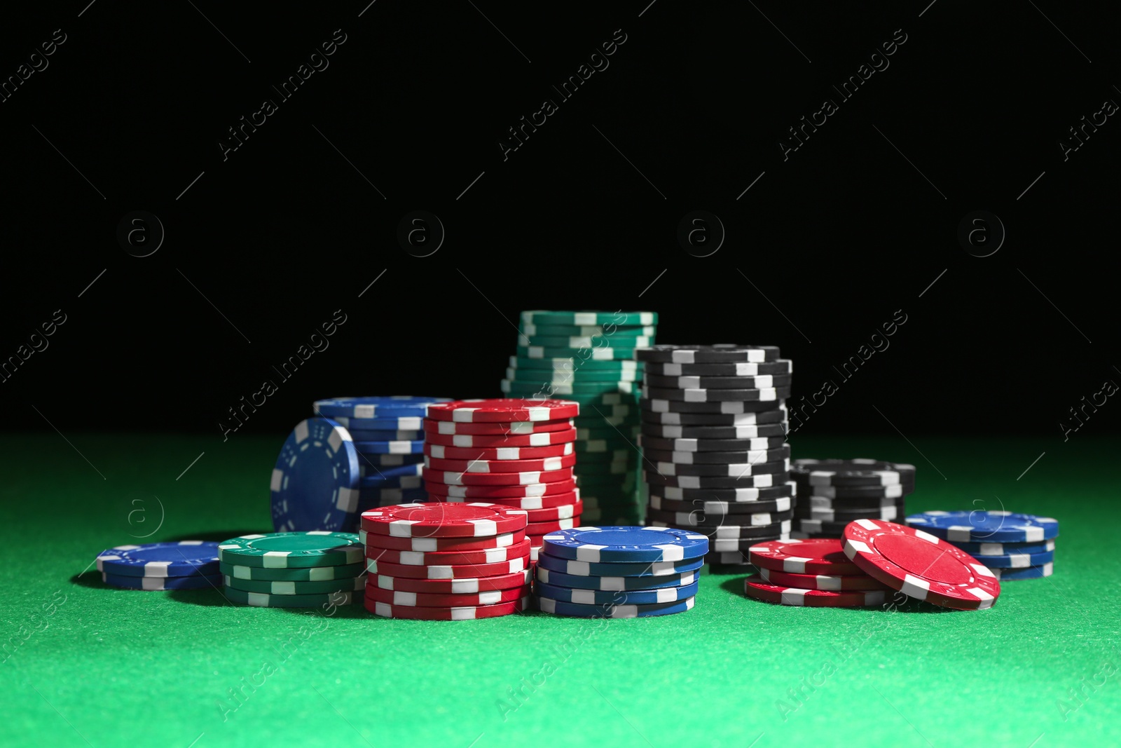 Photo of Poker chips on green table against dark background