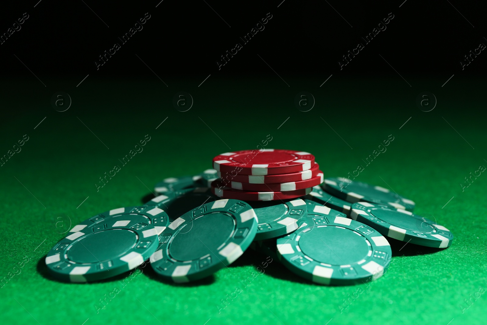 Photo of Poker chips on green table against dark background, closeup