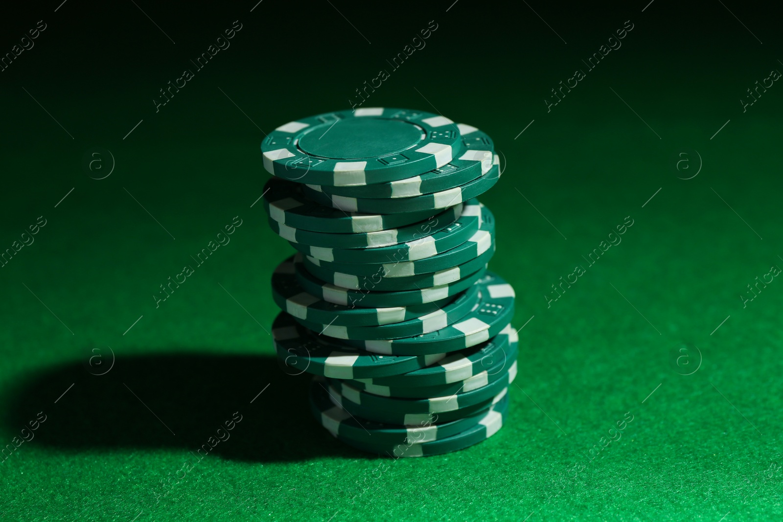 Photo of Stack of poker chips on green table, closeup