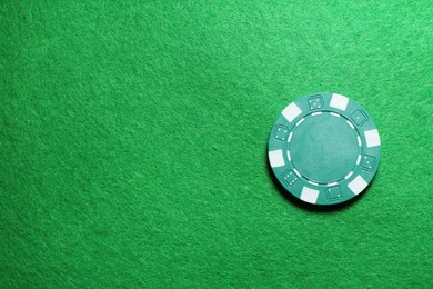 Photo of Poker chip on green table, top view. Space for text