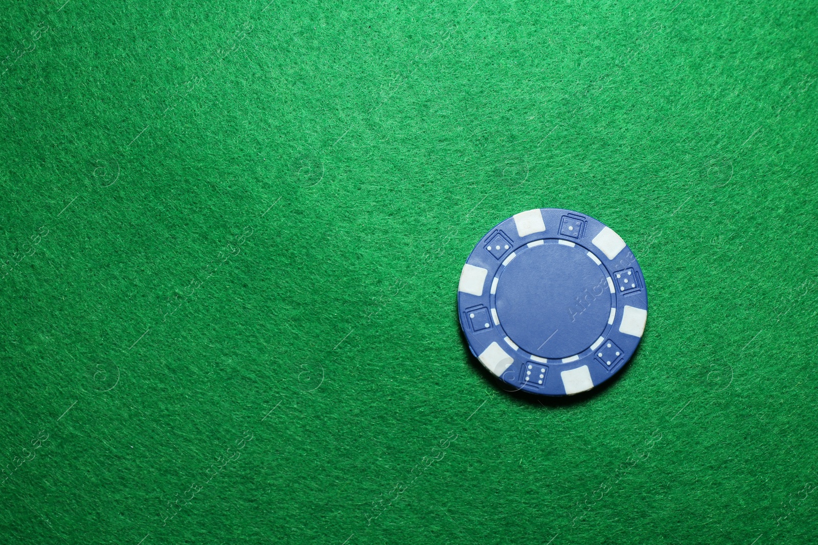 Photo of Poker chip on green table, top view. Space for text