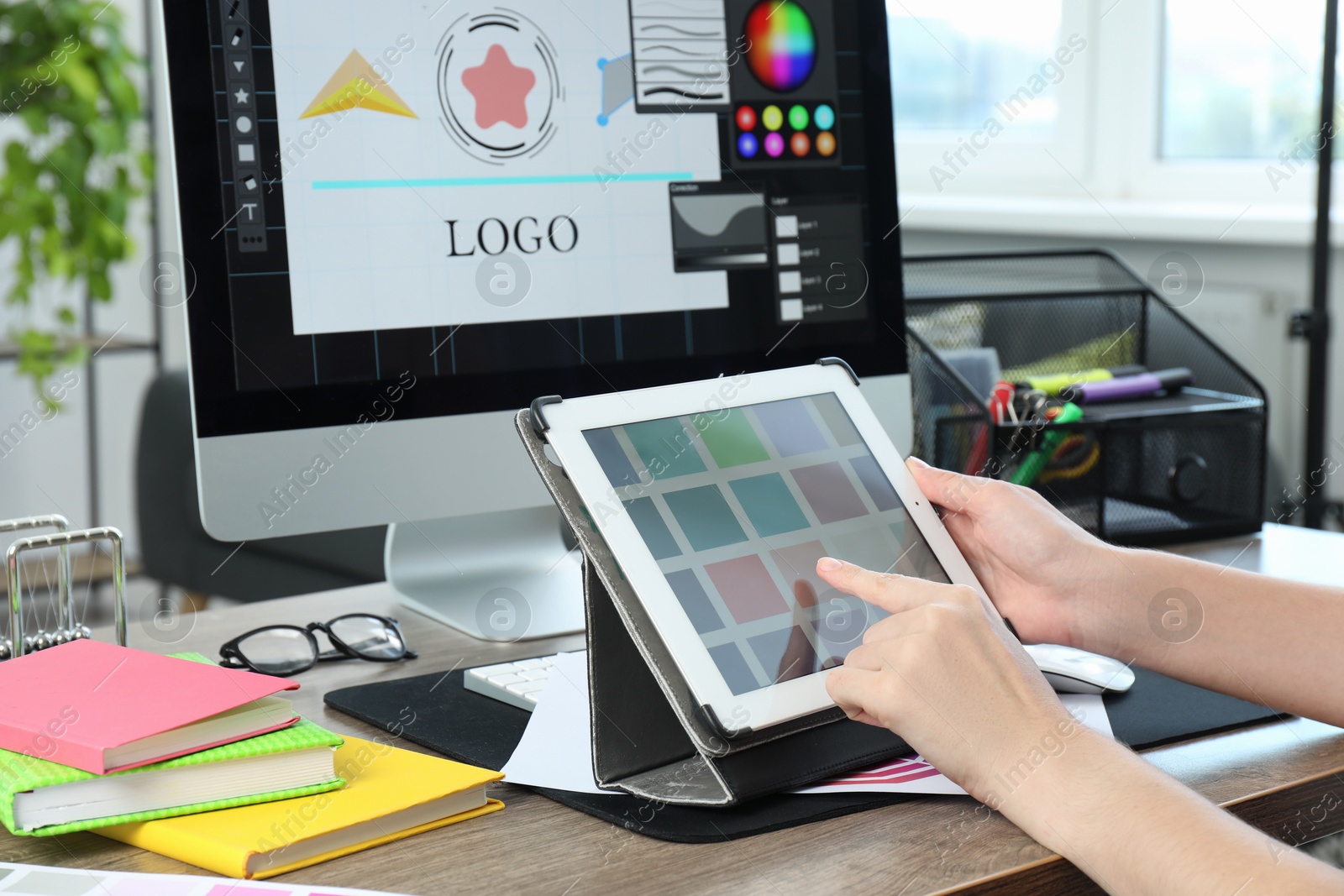 Photo of Designer working on tablet at wooden table indoors, closeup