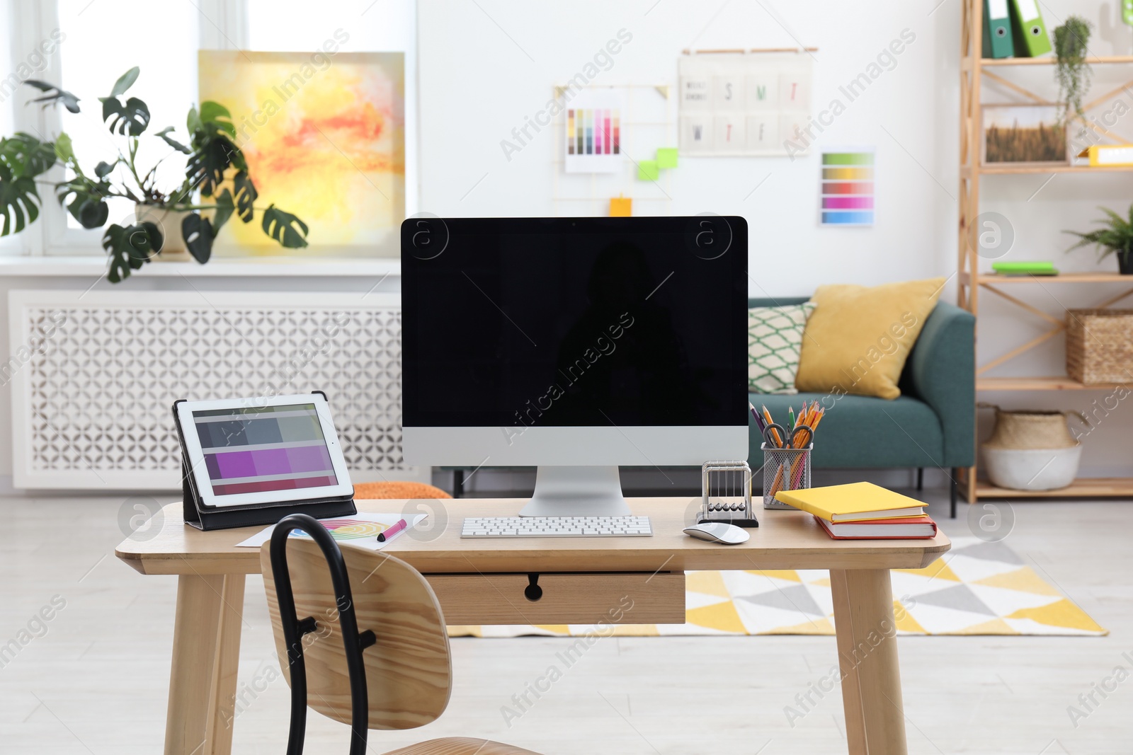 Photo of Designer's workplace with computer, tablet, color palette and stationery on wooden table indoors